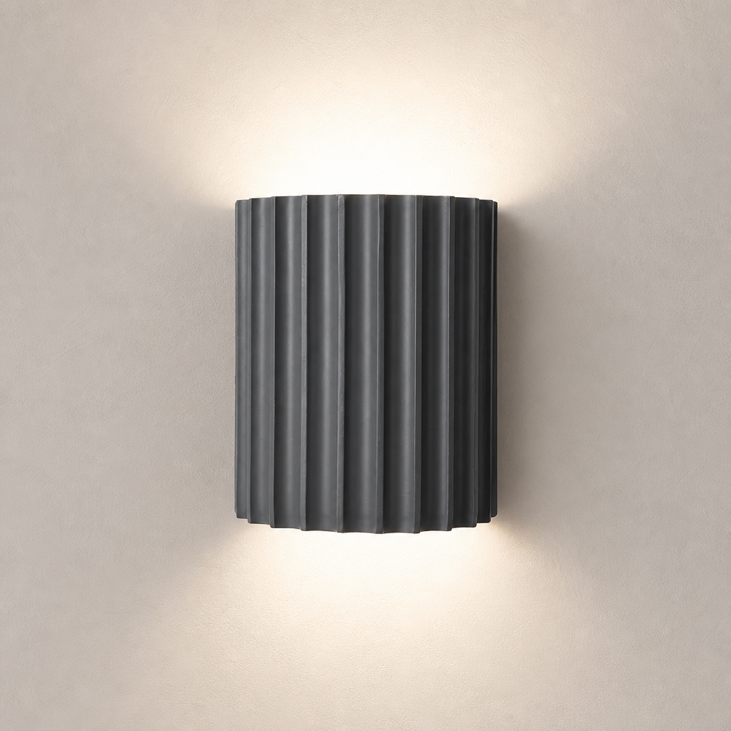 Dark ribbed cylindrical wall sconce emitting warm light above and below.