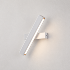 White diagonal LED wall sconce with warm light on a pale textured wall.