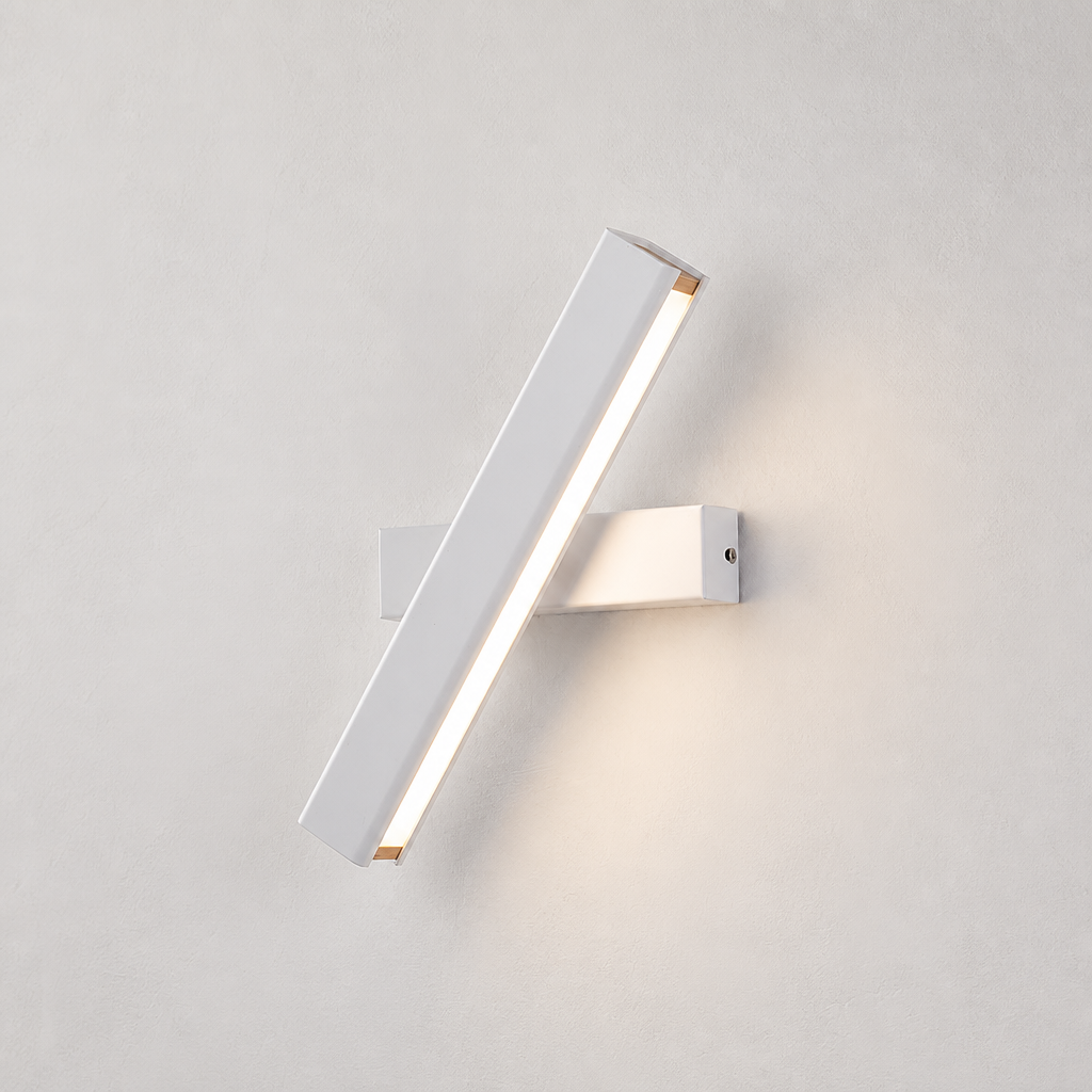 White diagonal LED wall sconce with warm light on a pale textured wall.