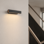 Black rectangular wall sconce with a warm downlight mounted on a pale modern interior wall.