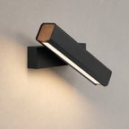 Black angled wall light with wood end caps mounted on a textured wall.