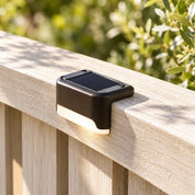 Daylight detail of a light positioned over a timber fence rail.