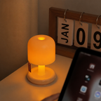 Small glowing mushroom-shaped lamp on a desk beside a calendar and tablet.