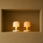 Two small glowing mushroom lamps, one white and one peach, sit side by side on a recessed shelf.