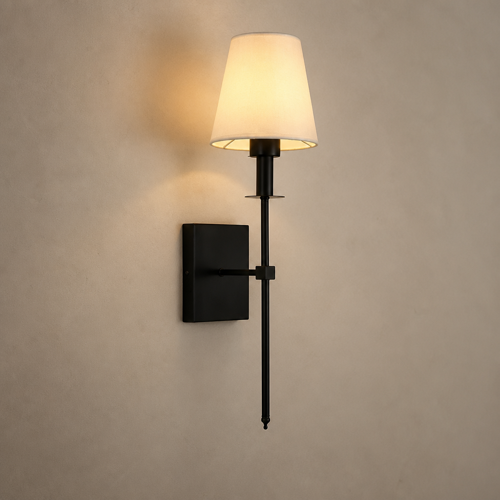 Black wall sconce with a glowing cream fabric shade mounted on a neutral wall.