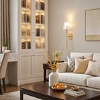 Gold wall sconce with white shade above a cozy sofa in a styled living room.