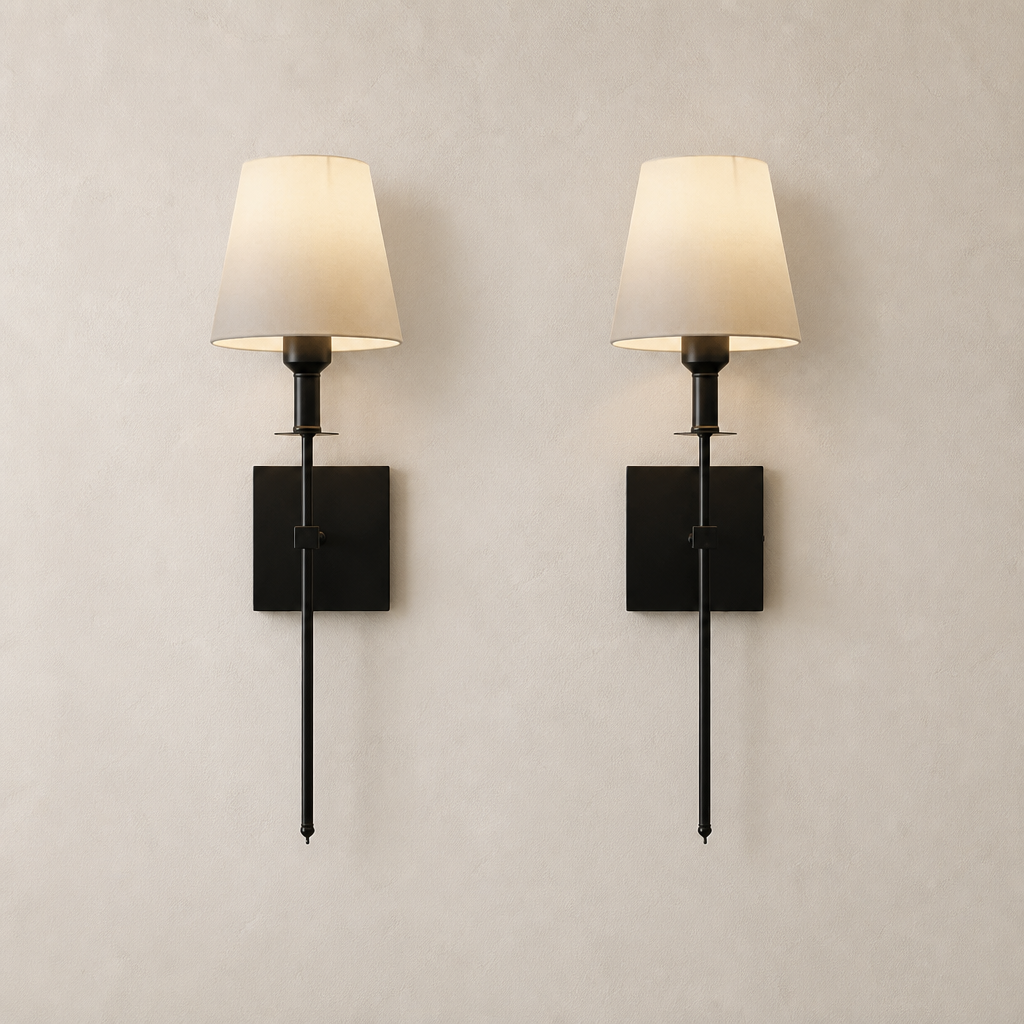 Pair of black wall sconces with cream fabric shades on a pale neutral wall.