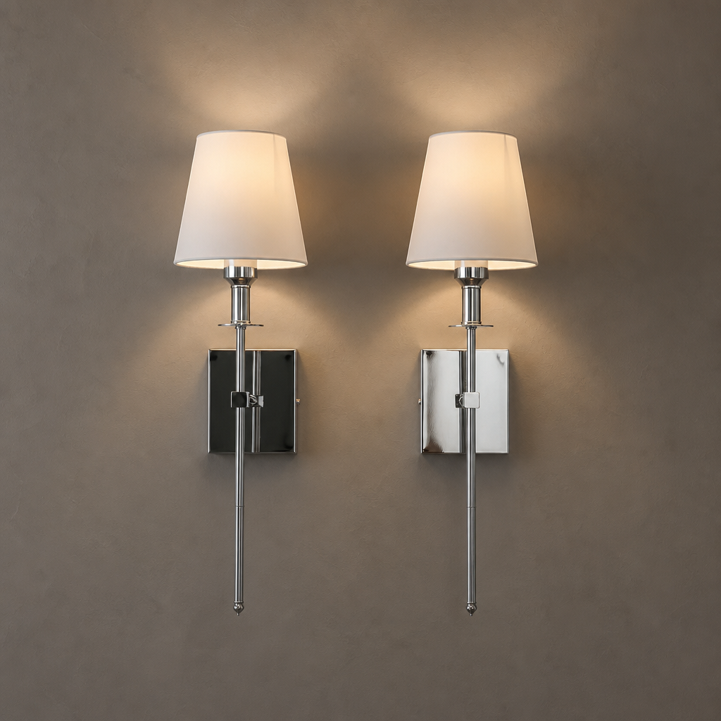 Two matching chrome wall sconces with cream shades glow on a warm gray wall.