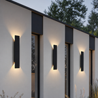 Black rectangular outdoor wall lights glow warmly on a modern white facade.