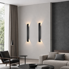Two slim black vertical wall sconces cast warm light on a modern living room wall.