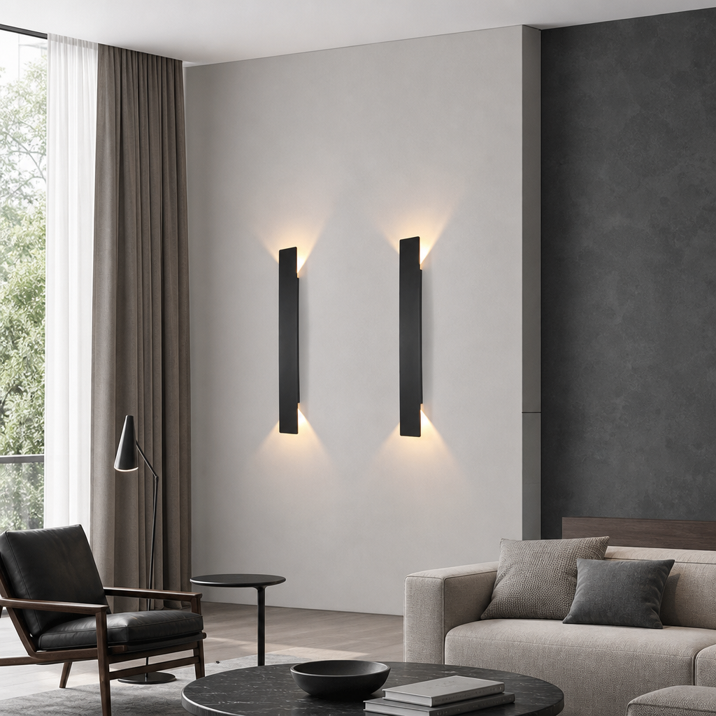 Two slim black vertical wall sconces cast warm light on a modern living room wall.