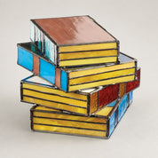 Stacked stained-glass boxes with yellow, blue, red, and amber panels on a plain studio background.