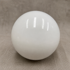 Glossy white spherical lamp shade on a neutral fabric surface.