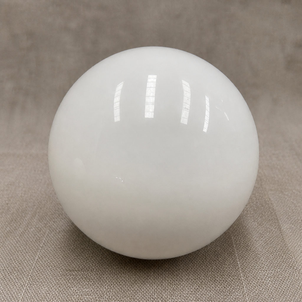 Glossy white spherical lamp shade on a neutral fabric surface.