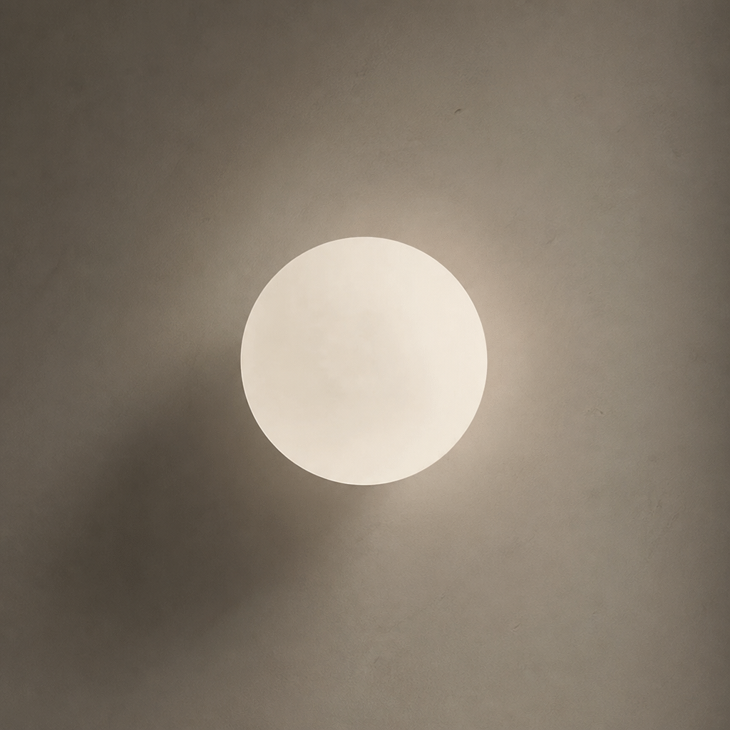 Glowing round white wall light on a muted beige wall.