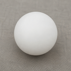 Smooth white spherical ball resting on a muted gray fabric surface.