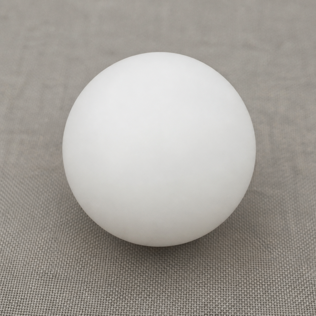 Smooth white spherical ball resting on a muted gray fabric surface.