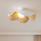Wavy white and wood ceiling light with a glowing round bulb mounted on a neutral ceiling.