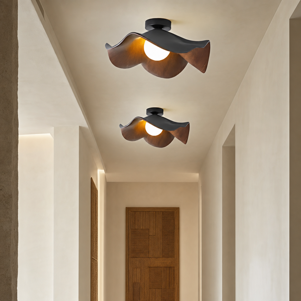 Two sculptural wood and black ceiling lights with glowing bulbs in a warm hallway.