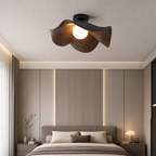 Wood-toned petal ceiling fan light with a glowing globe above a modern bedroom.