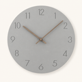 Round gray wall clock with thin black numbers and wooden hands on a light neutral background.