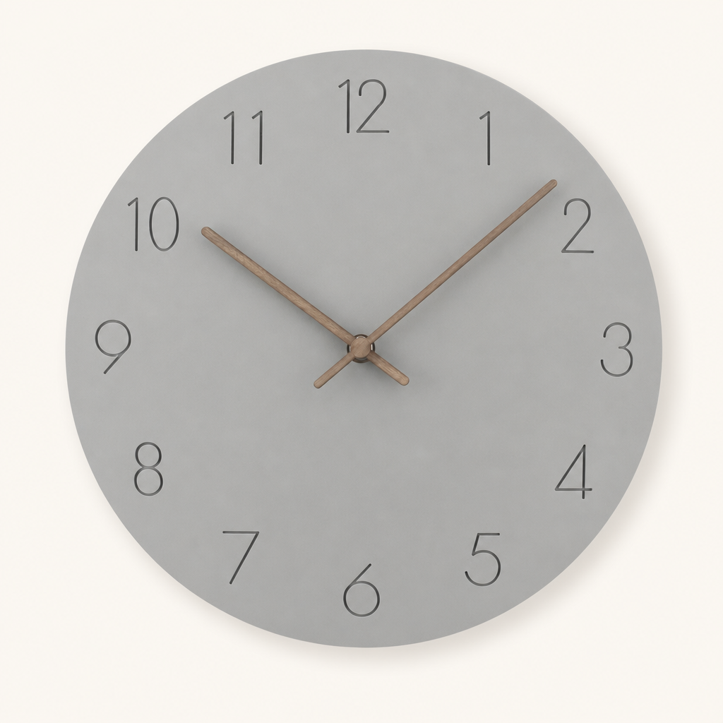 Round gray wall clock with thin black numbers and wooden hands on a light neutral background.