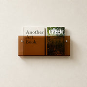 Amber wall-mounted magazine rack holding two books on a light textured wall.