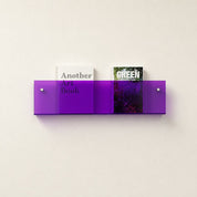 Translucent purple wall-mounted acrylic shelf holding two books on a light wall.