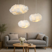 Three fluffy cloud pendant lights glow above a gray sofa with pillows and small tables.