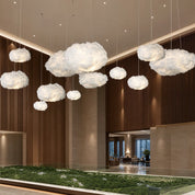 Glowing white cloud pendant lights suspended in a modern interior atrium.