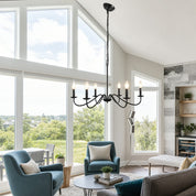 Black six-light candle chandelier hanging in a bright modern living room.