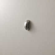 Shiny silver oval wall hook mounted on a light gray wall.
