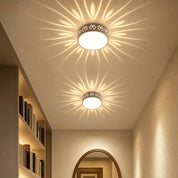 Two round ceiling lights cast floral light patterns in a warm hallway.