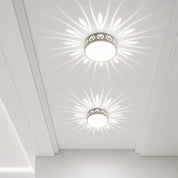 Two round flush ceiling lights with patterned rims casting floral rays on a white ceiling.