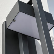 Gray and black angular outdoor wall light with a frosted rectangular panel and visible screw.