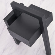 Black geometric shelving unit with angular tiers on a pale marble surface.