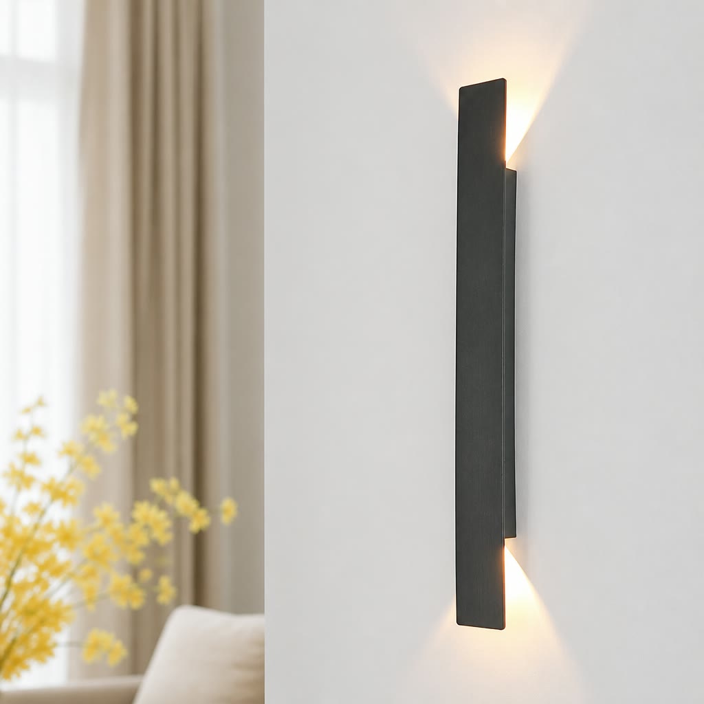 Black vertical wall sconce casts warm up-and-down light on a white wall.