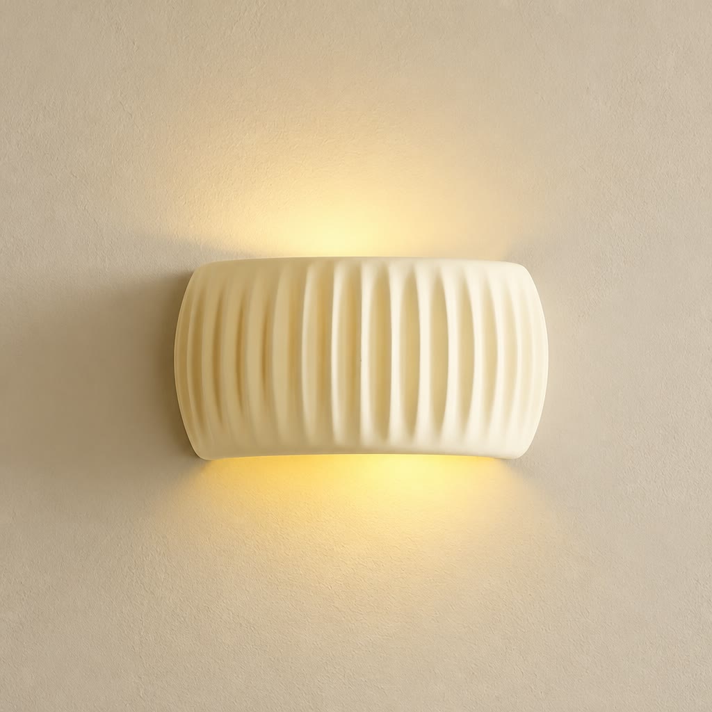Cream ribbed resin wall sconce glowing warmly on a pale textured wall.