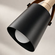 Black cylindrical pendant lamp shade with wood detail and visible white bulb.