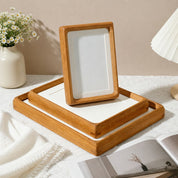 Wooden tray set with white inserts and a matching upright photo frame on a soft styled tabletop.