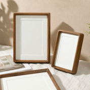 Three wooden photo frames with cream mats arranged on a light fabric surface.