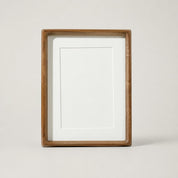 Wooden rectangular photo frame with white mat and blank center on a light neutral background.