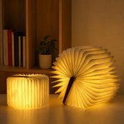 Two warm glowing foldable book lamps on a tabletop.