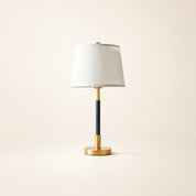 White shade table lamp with a black stem and polished gold base.