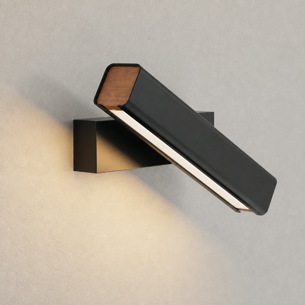 Black wall-mounted linear lamp with wood ends casting warm light on a textured wall.