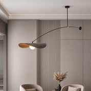 Modern black arc pendant lamp with petal shades and glowing bulb above a neutral living room wall.