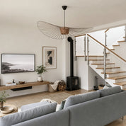 Sculptural wire pendant light above a neutral living room with stairs.