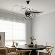 Black wire pendant lamp with a wide sculptural shade above a round dining table.