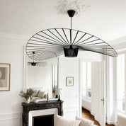 Black wire fan-shaped pendant light hanging in a bright white living room.