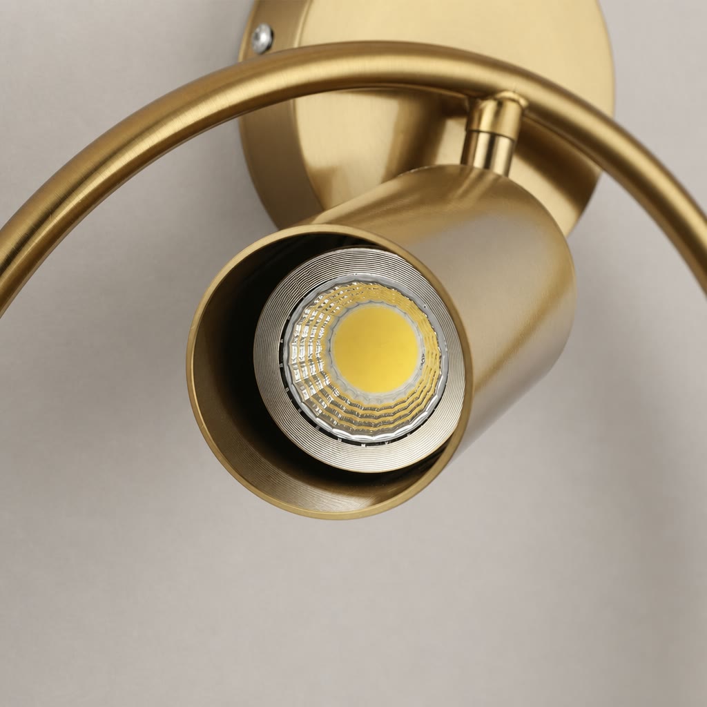Brushed gold adjustable spotlight with circular wall mount and exposed LED bulb.